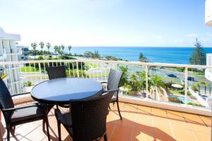 a balcony with a table and chairs and the ocean at Osprey Apartments in Mooloolaba