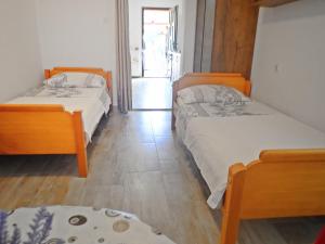two beds in a small room with wooden floors at Apartman MASLINA in Starigrad-Paklenica