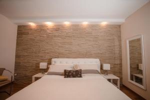 una camera con un letto bianco e un muro di mattoni di B&b Villa Maria Di Venere a Bari