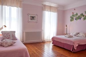 a bedroom with two beds and two large windows at Domaine du Prieuré Couvent & Presbytère in Carcassonne