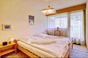 a bedroom with a large white bed with a window at Appartement à 200m de la télé-cabine de Vercorin in Vercorin