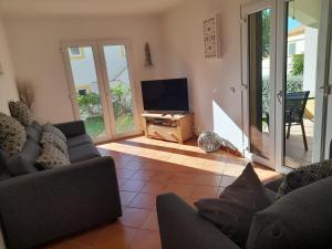 a living room with a couch and a flat screen tv at Garden Apartment Quinta do Morgado in Tavira