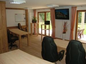une salle de conférence avec une table, des chaises et un tableau blanc dans l'établissement Alpenhof Reuterwanne, à Wertach