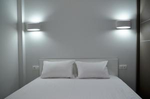 a white bed with two pillows and two lights on it at Ippokratio Luxury Apartment in Thessaloniki