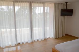 a bedroom with large windows with white curtains at Ruka Lobos in Pichilemu