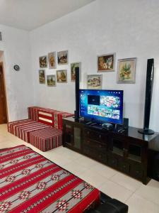 apartment in Ajman for 4 persons near the sea في عجمان: غرفة معيشة مع تلفزيون بشاشة مسطحة على خزانة