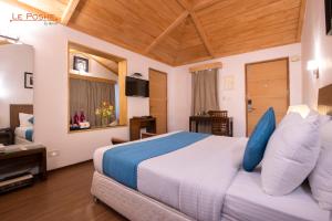 a bedroom with a large bed with blue pillows at Le Poshe, Kodaikanal in Kodaikānāl