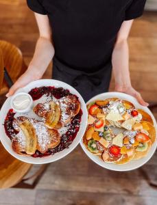 a person holding two white bowls of food at Moja Apartments Krakow Old Town in Krakow