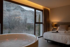 a bedroom with a tub and a bed with a view at Almazara Suites in Alcalá del Júcar