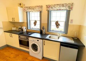 a kitchen with a sink and a washing machine at Pentland Farm Cottage Annex in Kirknewton