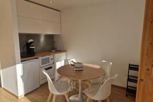 Una cocina con una mesa de madera y sillas blancas. en Rare pearl with an incredible view of all Briançon, en Briançon