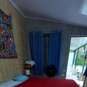 a bedroom with blue curtains and a bed and a mirror at chambre indépendante chez l'habitant in Parrita