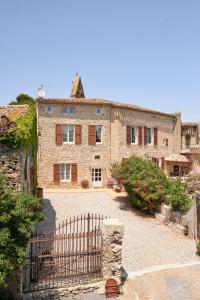 une grande maison en pierre avec un portail en face de celle-ci dans l'établissement Domaine du Prieuré Couvent & Presbytère, à Carcassonne