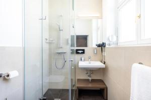 クラーゲンフルトにあるGarner Hotel Klagenfurt - Moser Verdino by IHGのガラスのシャワーと洗面台を備えたバスルーム +61枚の写真