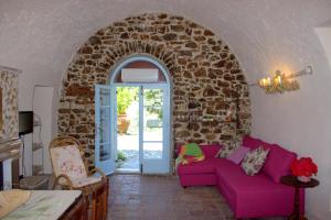 sala de estar con sofá púrpura y pared de piedra en Il Poggio di Teo, en Manciano
