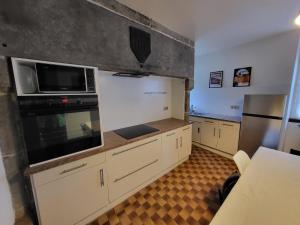een keuken met witte kasten, een magnetron en een koelkast bij Les Pénates Corréziennes in Dampniat