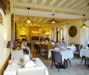 uma sala de jantar com mesas e cadeiras brancas em Logis L'auberge Du President em Cormeilles