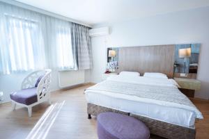 a hotel room with a large bed and a purple chair at Hotel Libiza in Gebze