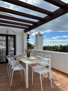 a white dining table and chairs on a balcony at Aldea Blanca Cozy Penthouse in Puerto Banús in Marbella