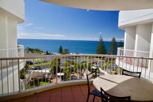 a balcony with a table and chairs and the ocean at Osprey Apartments in Mooloolaba
