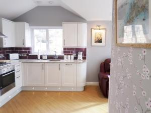 a kitchen with white cabinets and a sink at The Lodge, Polgooth in St Austell