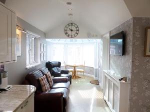 a living room with a couch and a clock on the wall at The Lodge, Polgooth in St Austell