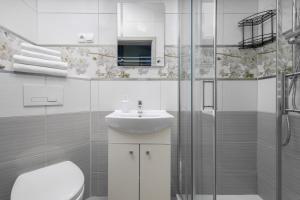 a white bathroom with a sink and a shower at Native Apartments Rakowicka 6 in Krakow