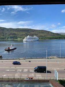 a large cruise ship in a large body of water at AK Lochview Apartment in Fort William