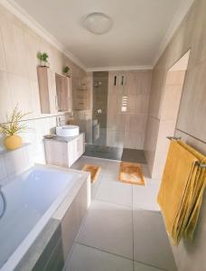 a bathroom with a tub and a sink and a shower at 25 On Rooiels in Hartenbos