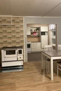 a kitchen with a stove and a table with chairs at Hotel Aakenus Holiday Home Santa in Rovaniemi