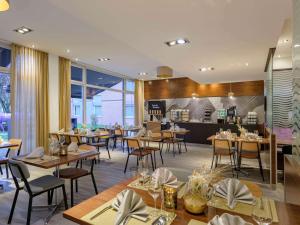 a restaurant with tables and chairs and a kitchen at Mercure Aachen Europaplatz in Aachen