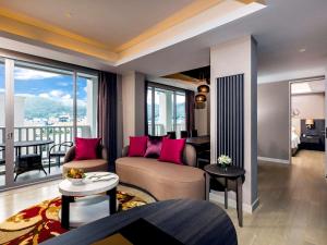 a living room with a couch and a large window at Grand Mercure Phuket Patong in Patong Beach