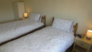 two beds in a small room with two lamps at Templecombe in Temple Combe