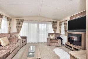 uma sala de estar com um sofá e uma televisão de ecrã plano em Spacious Stunning Lakeside 3 bed Holiday Home em Northampton