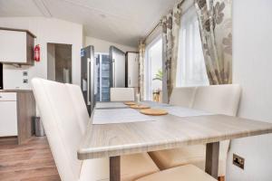 uma sala de jantar com uma mesa de madeira e cadeiras brancas em Spacious Stunning Lakeside 3 bed Holiday Home em Northampton