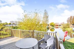 a deck with a table and chairs next to a lake at Spacious Stunning Lakeside 3 bed Holiday Home in Northampton