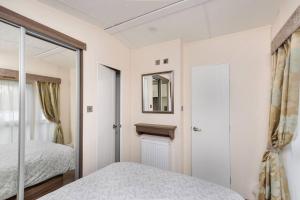 um quarto com uma cama e um espelho em Spacious Stunning Lakeside 3 bed Holiday Home em Northampton