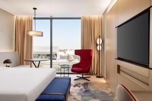 a bedroom with a bed and a red chair and a tv at Radisson Blu Hotel Riyadh Convention and Exhibition Center in Riyadh