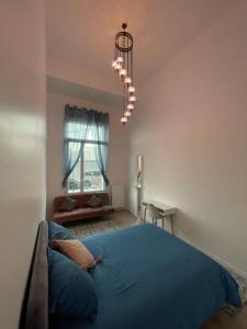 sypialnia z niebieskim łóżkiem i żyrandolem w obiekcie Nouvel appart bien-être/confort w mieście Saint-Ouen