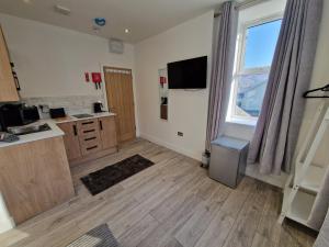 a room with a kitchen with a sink and a window at Flat 1, Modern studio apartment, Tynte Hotel, Mountain Ash in Quakers Yard