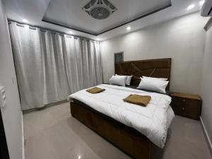 a bedroom with a large bed with two towels on it at 3 bed Luxurious Apartment DHA PH8 in Lahore