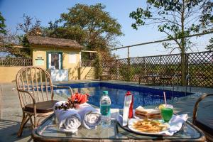 einen Tisch mit einem Tablett mit Essen neben einem Pool in der Unterkunft Asiatic Lion Lodge in Sasan Gir