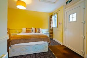 1 dormitorio con cama y pared amarilla en OYO The White Horse, Ripon North Yorkshire, en Ripon