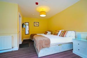 - une chambre avec 2 lits et un mur jaune dans l'établissement OYO The White Horse, Ripon North Yorkshire, à Ripon
