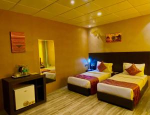 a hotel room with two beds and a mirror at Ace Prime Hotel in Greater Noida