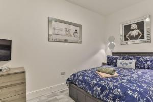 a bedroom with a blue bed and a tv at The Monroe - 2nd Floor - Luxury for up to 4 guests near Open Air Theatre and North Bay in Scarborough
