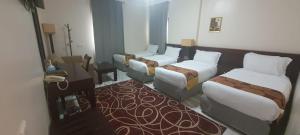 a hotel room with three beds and a table at Durrat Mina Hotel in Mecca
