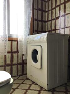 uma máquina de lavar roupa na casa de banho ao lado de um WC em Casa Tino 2 em Montederramo