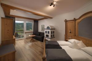 ブルーニコにあるSchönblick - Sport & Active Hotelのベッドルーム1室(ベッド1台、ソファ、窓付)