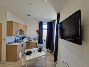 a kitchen with a table and a tv on a wall at Flat 2, Modern Studio apartment, Tynte Hotel, Mountain Ash in Quakers Yard